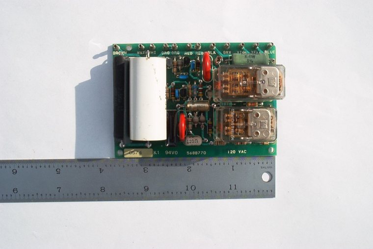 Compact 120 V AC legacy control board with two plug-in relays, photographed against a steel rule for scale
