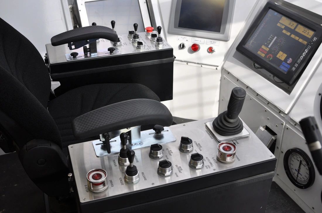 Drillers chair with armrest mounted joystick control panels facing touchscreen displays
