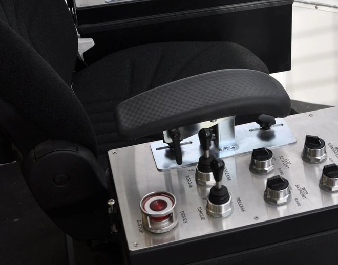 Armrest control pod on a drillers chair with joystick, toggle levers, illuminated E-stop, & legended rotary selectors