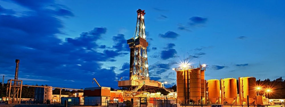 Land drilling rig and field equipment at dusk